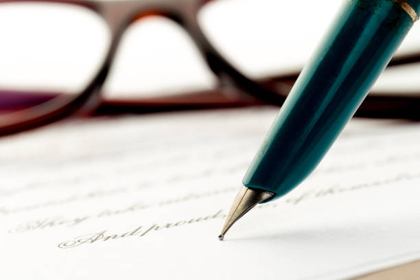 istock white fountain pen on letter, glasses behind 1086532888