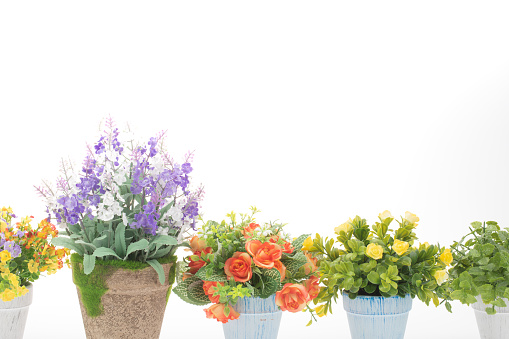 Rows of colorful fake flowers on white background, made from cloth and plastic for decoration.