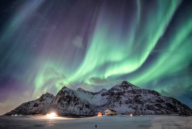 istock Aurora borealis with starry over snow mountain range with illumination house in Flakstad, Lofoten islands, Norway 1086544774