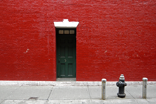 a house with red walls and a fire hydrant at the gate