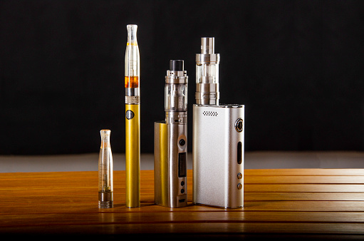 Popular vaping e cig devices mod.electronic cigarette over a wood background. vaporizer e-cig old device model.