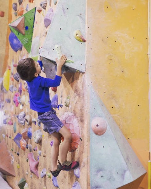 istock Little boy climbing a rock wall indoor. 1086560612