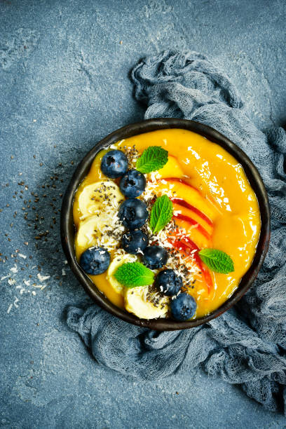 Mango smoothie bowl with fresh ripe berries and fruits
