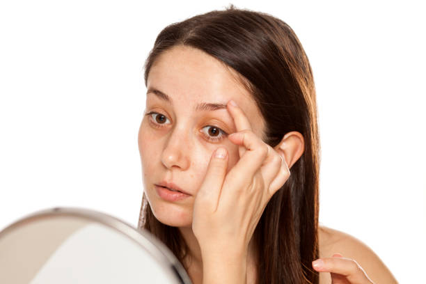 istock Beautiful young woman touch her  eyebrow in mirror on white background 1086566812
