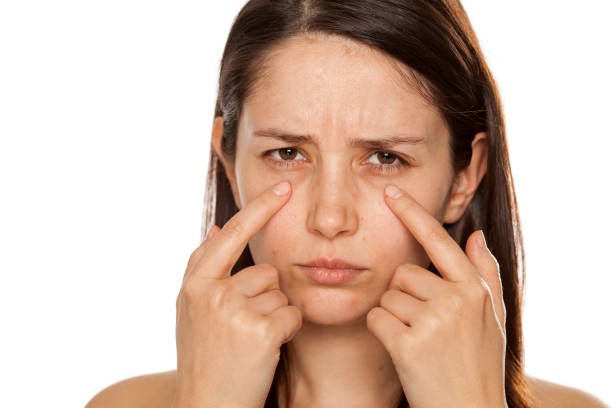 istock Beautiful young woman touch her face under eyes on white background 1086566826