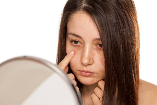 istock Unsatisfied young woman touch her face in mirror on white background 1086566828