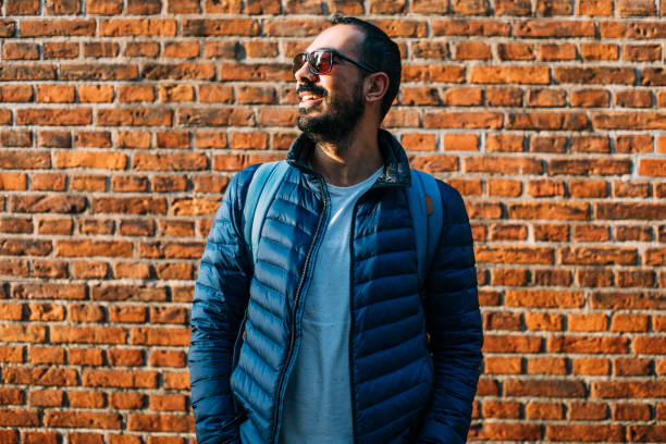 Cheerful laughing young man near the brick wall