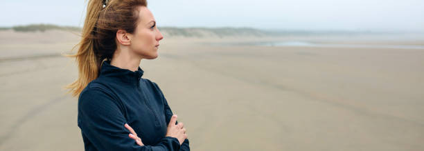 Woman looking at sea Woman looking at sea on the beach in autumn walking beach women sadness stock pictures, royalty-free photos & images