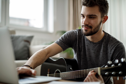 Young man playing a guitar at home