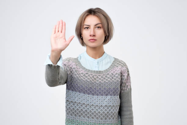 istock Serious young woman standing with outstretched hand showing stop gesture 1086607752