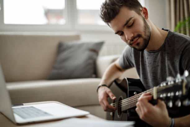 istock Young man playing a guitar at home 1086607766
