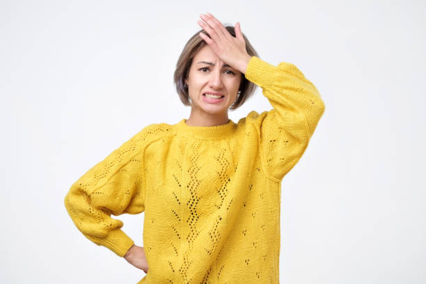 Portrait of excited young woman in yellow sweater holding her head stock photo