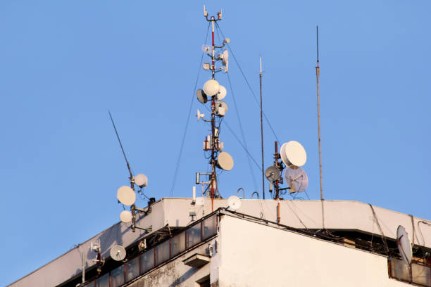 istock Telecommunication base stations network repeaters on the roof of building. The cellular communication aerial on city building roof. Cell phone telecommunication tower. Antennas on top of building. 1086612074