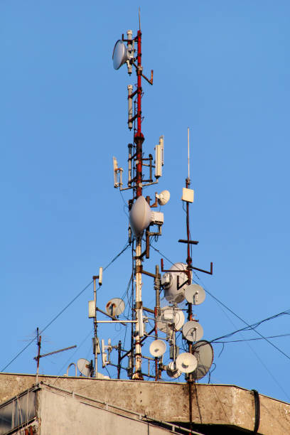 istock Telecommunication base stations network repeaters on the roof of building. The cellular communication aerial on city building roof. Cell phone telecommunication tower. Antennas on top of building. 1086612092