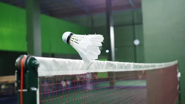 Closeup of badminton shuttlecock flying across the net.