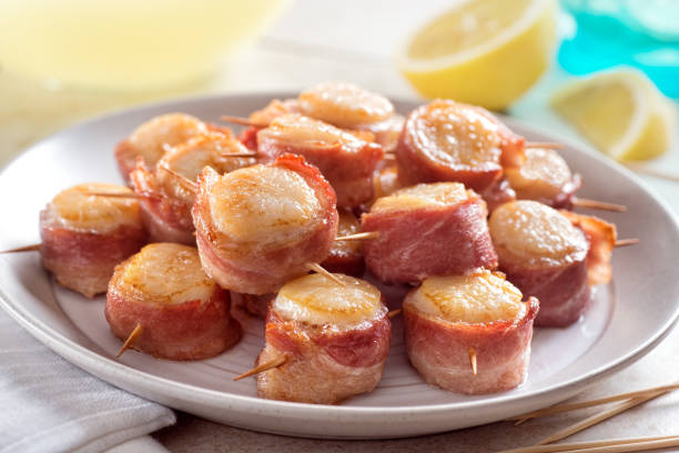 Bacon Wrapped Scallops A plate of delicious bacon wrapped scallops with lemon. bacon wrapped stock pictures, royalty-free photos & images
