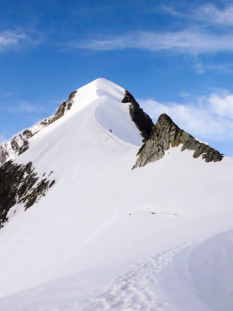 bergsteiger auf einem steilen und schmalen schneegrat führt zu einem hohen gipfel in den schweizer alpen - biancograt stock-fotos und bilder