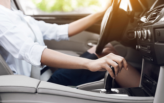 Business woman driving and shifting automatic transmission, side view