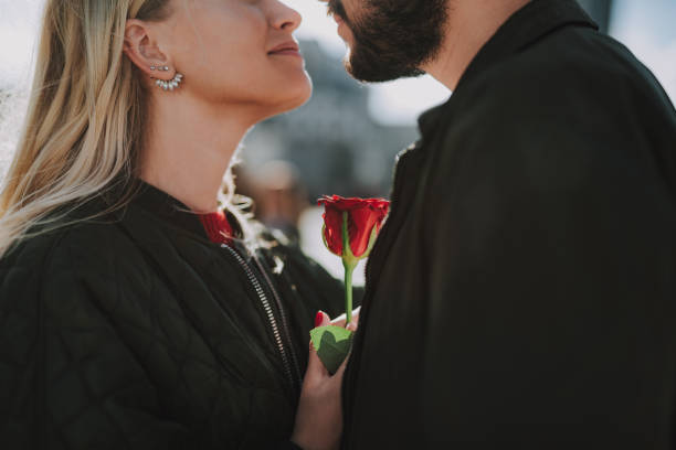 istock Loving young couple holding beautiful flower while standing close to each other 1086628522