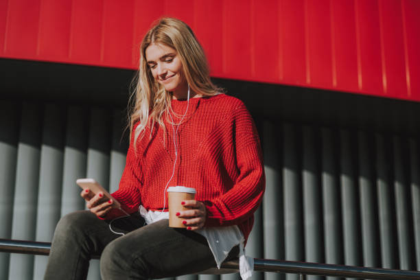 istock Attractive young lady with hot drink using cellphone on the street 1086628546