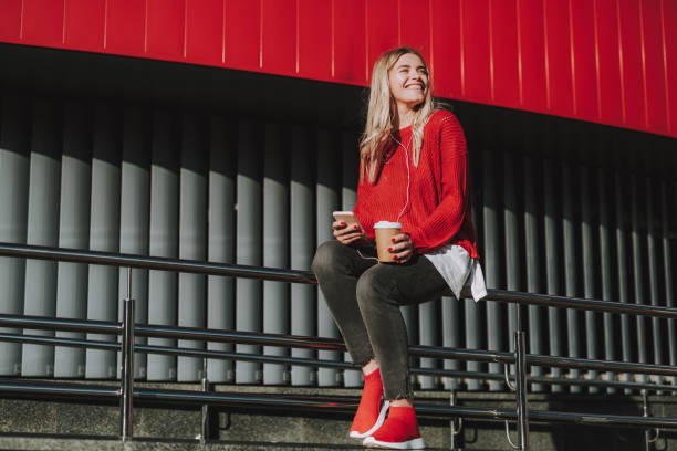 istock Charming young lady with hot drink using cellphone outdoors 1086628562