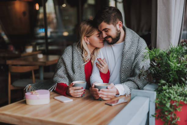 istock Beautiful young couple in warm blankets cuddling at cafe 1086628608