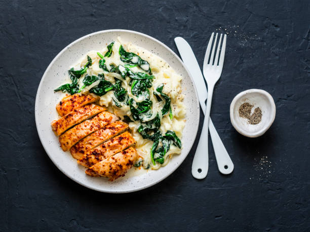 Baked chicken breast, mashed potatoes with creamy spinach on dark background, top view. Comfort food