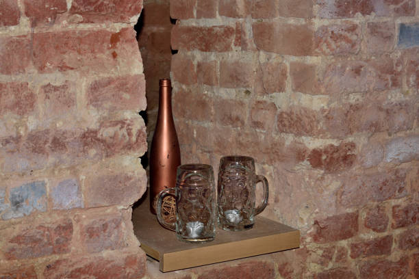 istock Two beer mugs and a brown bottle between two brick walls 1086646188