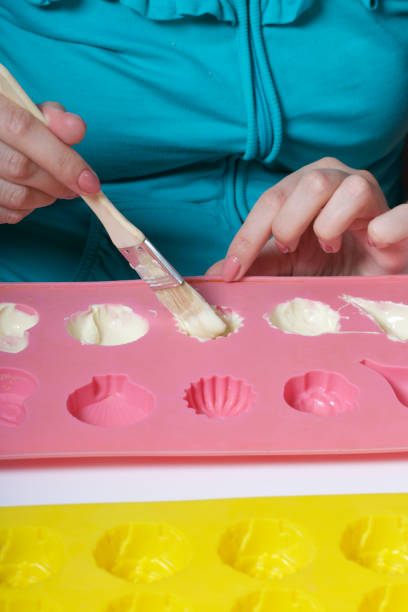 istock A woman using a brush brushes a melted chocolate silicone mold for dessert. 1086668002