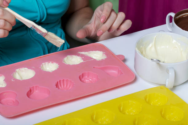 istock A woman using a brush brushes a melted chocolate silicone mold for dessert. 1086668226