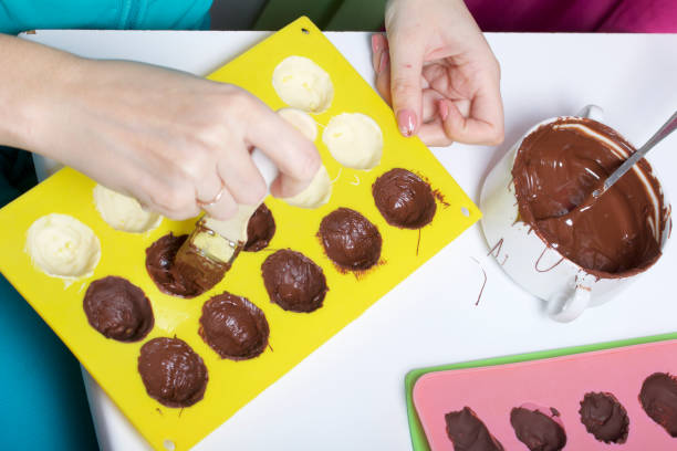 istock A woman using a brush brushes a silicone dessert mold with a melted black chocolate. Nearby are other ingredients. 1086668746