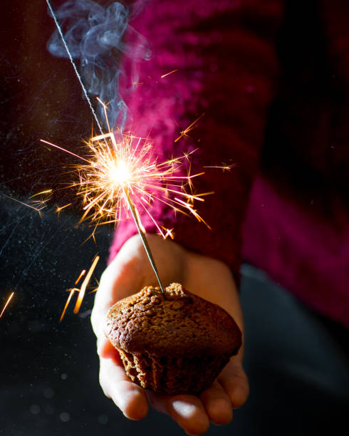 istock guy in a sweater holding a chocolate muffin with a burning sparkler 1086671176