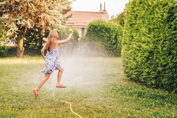 istock Child playing with garden sprinkler, jumping over 1086673048