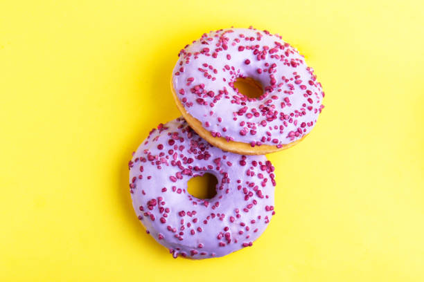istock Two delicious lilac donuts with sprinkle on bright yellow background. 1086680112