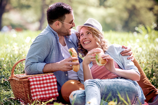 Couple in love having picnic in a park,eating sandwiches  and enjoying the day.