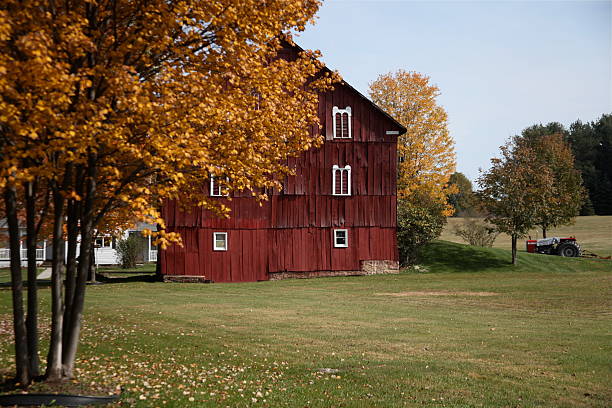 istock Red barn fall foliage in pasture with tractor 108668710