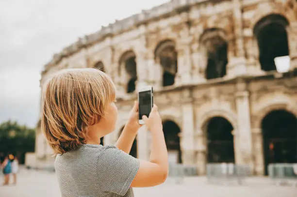 Little boy tourist taking pictures of  Arena of NÃ®mes, France
