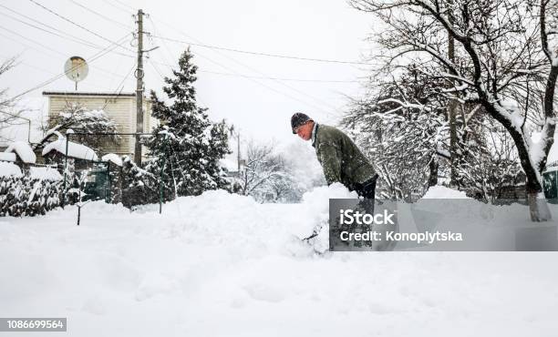 Man With A Shovel Cleans The Track From The Snow Stock Photo - Download Image Now - Snow, Digging, Shovel
