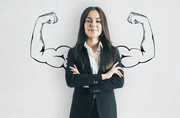 Portrait of attractive young european businesswoman with drawn muscly arms. Confidence and strength concept
