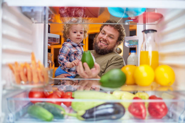 istock Father and son taking food from fridge late at night. 1086701278