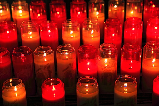 Hope: Light in the darkness: group of burning candlelight inside church on black background