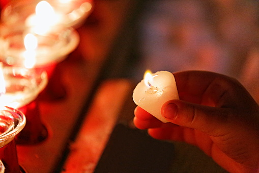 Hope: Light in the darkness: helping hand offering candlelight inside church