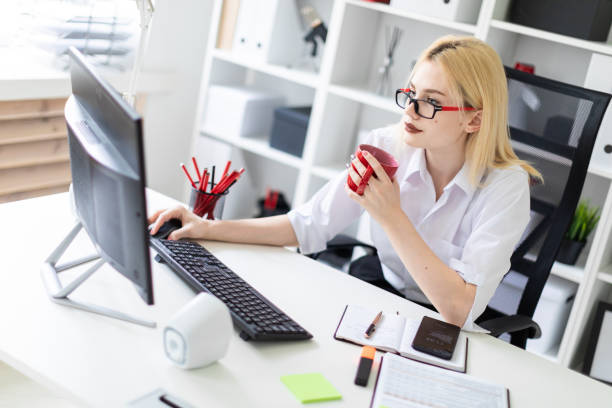 istock A young girl working at a computer in the office and holding a red Cup. 1086725308