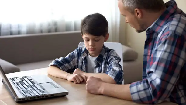 Photo of Strict father scolding his little son for computer addiction, family problem