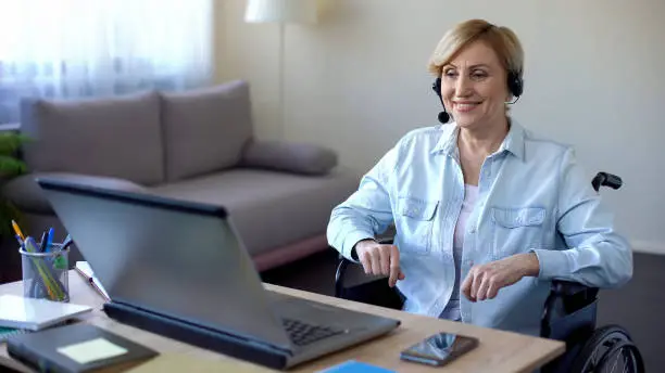 Senior businesswoman in wheelchair working in office, video conference online