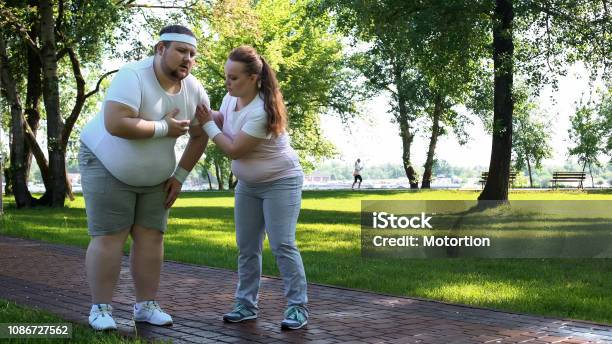 뚱뚱한 남성 조깅 뚱뚱한 여자 친구 지원 그를 돕는 동안 심장 아픔을 느낀다 건강관리와 의술에 대한 스톡 사진 및 기타 이미지 -  건강관리와 의술, 건강한 생활방식, 공격성 - iStock 뚱뚱한 남성 조깅 뚱뚱한 여자 친구 지원 그를 돕는 동안 심장 아픔을 느낀다 건강관리와 의술에 대한 스톡 사진 및 기타 이미지 -  건강관리와 의술, 건강한 생활방식, 공격성 - Istock