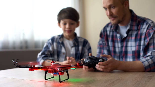 istock Father helping pleased son to use remote control of quadrocopter, technologies 1086727568