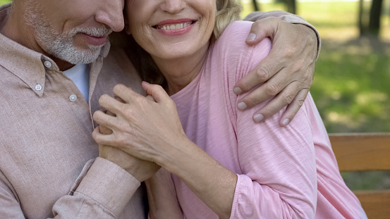 Loving senior couple embracing in park, comfortable retirement, secure old age