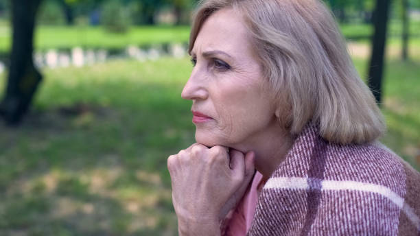 istock Thoughtful aged lady covered with plaid blanket sitting on bench in garden 1086728130