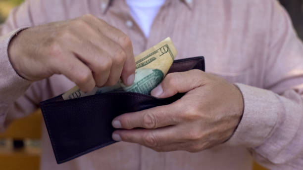 istock Poor pensioner putting dollar banknote in empty wallet, low retirement payment 1086728458